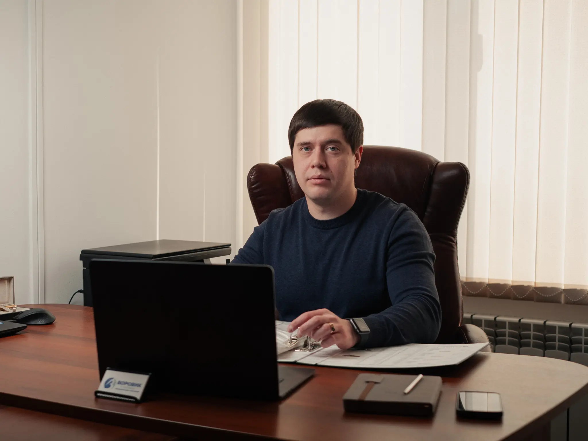 Юрист по спорам с Россетями Дмитрий Боровик за рабочим столом изучает документы по технологическому присоединению к электросетям